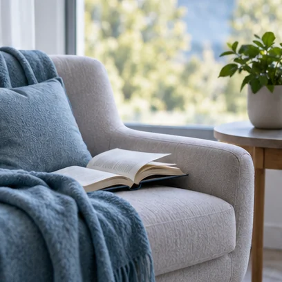 Livre ouvert sur un fauteuil, a cote d’une fenetre.