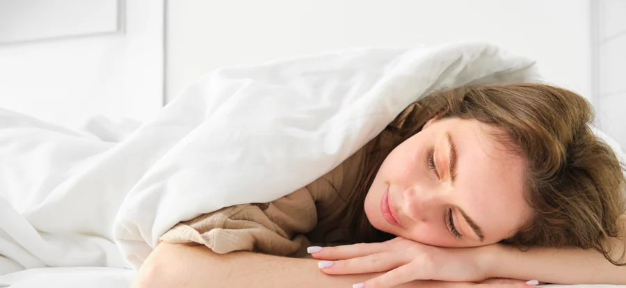 Une personne endormie sous une couette blanche. Photographie d’illustration.